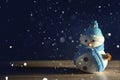 Happy snowman standing in dark winter christmas snow background. Merry christmas and happy new year greeting card with copy-space. Royalty Free Stock Photo