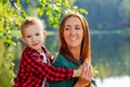 Happy son on the background of the lake hugs a young smiling mother behind the neck. Parenting, family day may 15, love, parents, Royalty Free Stock Photo