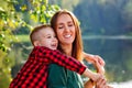 Happy son on the background of the lake hugs a young smiling mother behind the neck. Parenting, family day may 15, love, parents, Royalty Free Stock Photo