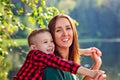 Happy son on the background of the lake hugs a young smiling mother behind the neck. Parenting, family day may 15, love, parents, Royalty Free Stock Photo