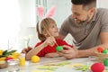 Happy son with bunny ears headband and his father painting Easter egg at table Royalty Free Stock Photo