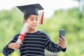 Happy Southeast Asian schoolgirl with a certificate and smartphone during graduation in Thailand Royalty Free Stock Photo