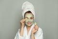 Happy spa woman in moisturizing cosmetic face mask with green organic cucumber. Facial treatment and skin care concept