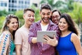 Happy spanish hipster student with tablet computer and group of cheering international students