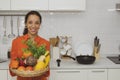 Happy spanish smiling woman holding fruit tray in white modern kitchen.