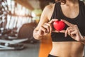 Happy sport woman holding red heart in fitness gym club. Medical cardio heart strength training lifestyle. Pretty female sport