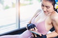 Happy sport woman using smart phone and wear headphones for listening music at fitness center during taking a rest of exercise Royalty Free Stock Photo