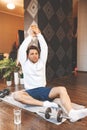 Happy sportive man doing yoga, sitting in lotus pose on the mat, smiling. Handsome athletic male meditates to deal with Royalty Free Stock Photo