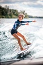 Happy sportive woman riding surf board on the wave from motor boat Royalty Free Stock Photo