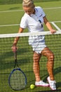 Happy sports girl stands with racket on court at sunny summer day