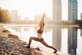 Sportswoman exercising on riverbank at sunrise