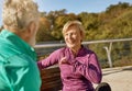 Happy sporty senior couple resting, sitting on the bench after workout outdoors. Mature woman smiling to man while Royalty Free Stock Photo