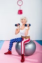 happy sporty senior woman with dumbbells sitting on fitness ball and smiling Royalty Free Stock Photo