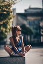 Happy sporty woman fitness trainer in sportswear sits on bench form on city street doing yoga exercises in Dubai Royalty Free Stock Photo