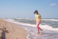 Happy sporty woman, with flying hair, is walking along the surf Royalty Free Stock Photo