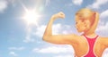 Happy sporty woman showing biceps over sky and sun Royalty Free Stock Photo