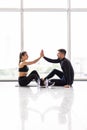 Happy sporty young couple relaxing after hard training and giving high five each other in gym Royalty Free Stock Photo