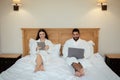 Happy Spouses Browsing Internet On Computers Sitting In Bed Indoors Royalty Free Stock Photo