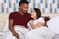 Happy spouses hug in bed in morning, smile and caress each other. Room, bed, pillows, husband and wife, relaxing at weekend, spend Royalty Free Stock Photo