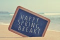 Happy spring break in a blackboard on the beach, with a filter e Royalty Free Stock Photo