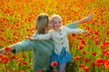 Happy spring family. Carefree mom with a child girl in a field of red poppies enjoys nature. Mother and little daughter Royalty Free Stock Photo