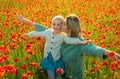 Happy spring family. Carefree mom with a child girl in a field of red poppies enjoys nature. Mother and little daughter Royalty Free Stock Photo