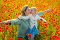 Happy spring family. Mother with daughter on the poppies meadow. Beautiful mom and daughter on a poppy field outdoor Royalty Free Stock Photo