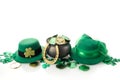 Happy St. Patrick's day. Shiny shamrocks, gold coins and leprechaun hat on white backgorund. Royalty Free Stock Photo