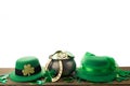 Happy St. Patrick's day. Shiny shamrocks, gold coins and leprechaun hat on wooden table isolated on white backgorund. Royalty Free Stock Photo