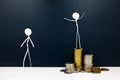 Happy stick man figure standing on a pile of coins beside a sad envious one. Rich versus poor and income inequality concept.