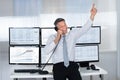 Happy stock trader pointing upwards while using telephone Royalty Free Stock Photo