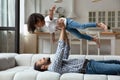 Happy strong dad lifting little daughter girl up in air