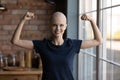 Happy strong female cancer patient flexing hands, biceps and fists