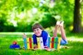 Happy student boy relaxing in school yard reading books Royalty Free Stock Photo