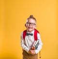 Happy student boy with school bag and books. Kid in glasses isolated on yellow background. Happy pupil of primary school Royalty Free Stock Photo