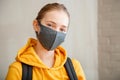 Happy student on brick wall background with copy space. Young beautiful woman smiles sincerely, wearing protective mask portrait