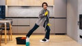 Happy student or business woman cleaning home, singing using mop like microphone and having fun while she wipes the floor. Young Royalty Free Stock Photo