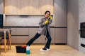 Happy student or business woman cleaning home, singing using mop like microphone and having fun while she wipes the floor. Young Royalty Free Stock Photo