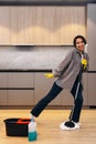 Happy student or business woman cleaning home, singing using mop like microphone and having fun while she wipes the floor. Young Royalty Free Stock Photo