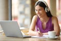 Happy student e-learning taking notes in a bar terrace Royalty Free Stock Photo