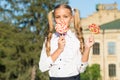 Happy student girl eat colorful lollipop outdoors, yummy dessert concept