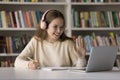 Happy student girl in headphones enjoying studying in library Royalty Free Stock Photo