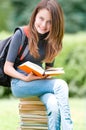 Happy student girl sitting on pile of books Royalty Free Stock Photo