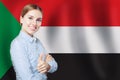 Happy student girl with thumb up against the sudan flag