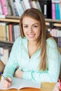 Happy student girl writing to notebook in library Royalty Free Stock Photo