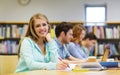 Happy student girl writing to notebook in library Royalty Free Stock Photo