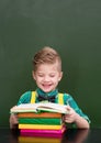 Happy student reading a book near empty green chalkboard Royalty Free Stock Photo