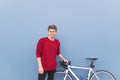 Happy student standing at a white bicycle on a blue background, looking into the camera and smiling Royalty Free Stock Photo