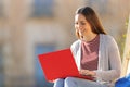 Happy student using red laptop sitting in a campus Royalty Free Stock Photo