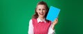 Happy student woman showing blue notebook isolated on green Royalty Free Stock Photo